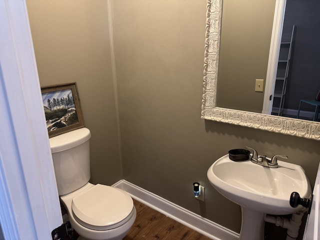 bathroom featuring toilet, wood finished floors, baseboards, and a sink