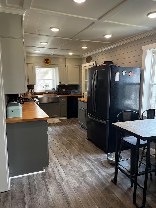 kitchen with black appliances, ornamental molding, a sink, dark wood finished floors, and wooden counters