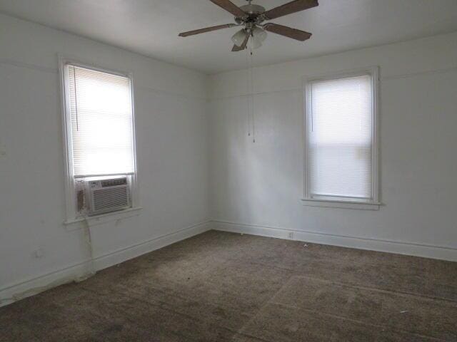 spare room featuring ceiling fan, cooling unit, and dark carpet