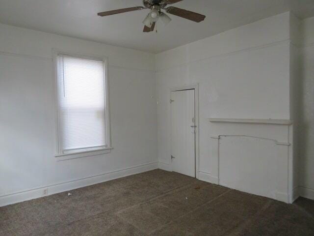 spare room featuring ceiling fan and dark carpet