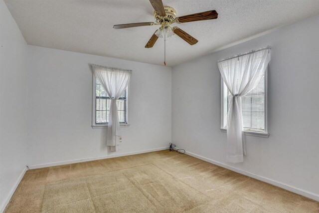 empty room with light carpet, a textured ceiling, and ceiling fan