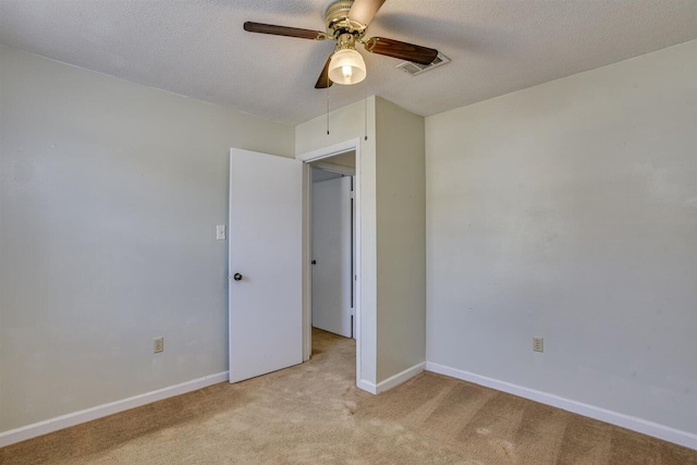 carpeted spare room with a textured ceiling and ceiling fan