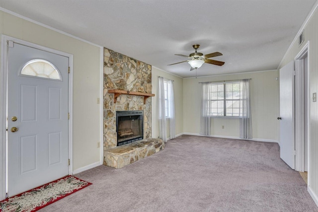 unfurnished living room with ceiling fan, a stone fireplace, crown molding, light colored carpet, and a textured ceiling