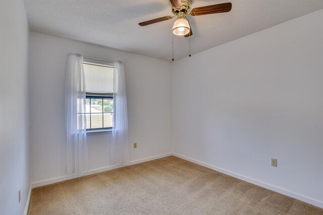 empty room with carpet flooring, ceiling fan, and a textured ceiling