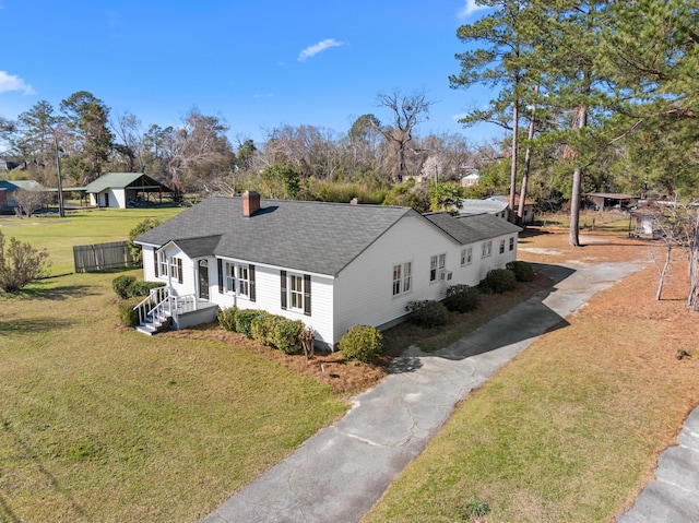 view of front of property featuring a chimney, fence, a front lawn, and roof with shingles