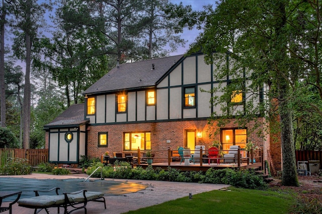 710 Somerset Way, Augusta, GA 30909 - back of property at dusk featuring a deck, stucco siding, brick siding, a shingled roof, and a patio