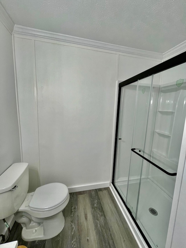 bathroom featuring hardwood / wood-style floors, toilet, ornamental molding, a textured ceiling, and an enclosed shower