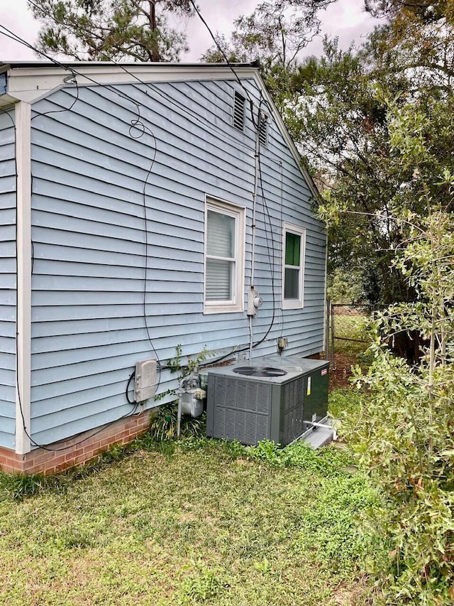 view of home's exterior featuring central AC unit and a lawn