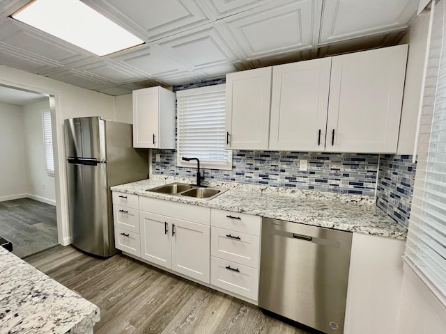 kitchen featuring light stone countertops, white cabinetry, sink, appliances with stainless steel finishes, and light wood-type flooring