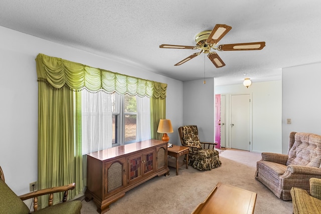 sitting room with ceiling fan, light carpet, and a textured ceiling