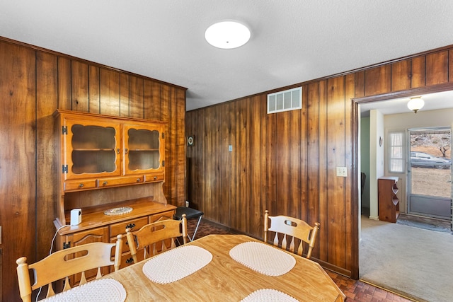 carpeted dining area featuring wood walls