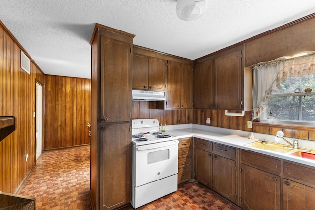 kitchen featuring sink, white electric range oven, a textured ceiling, and wooden walls