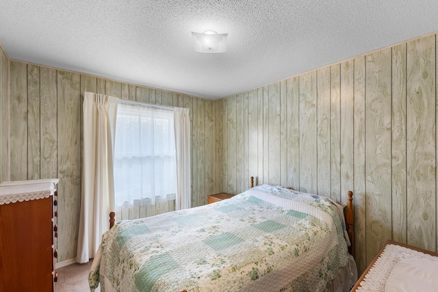 bedroom with wood walls, carpet, and a textured ceiling