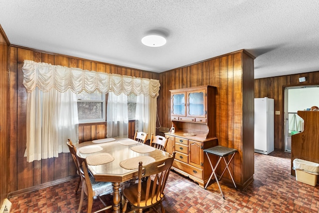 dining space featuring wooden walls and a textured ceiling