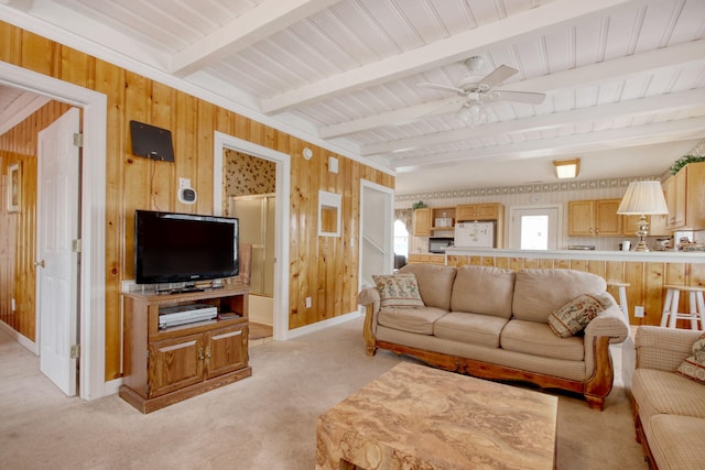 living room with light colored carpet, ceiling fan, wooden walls, and beamed ceiling