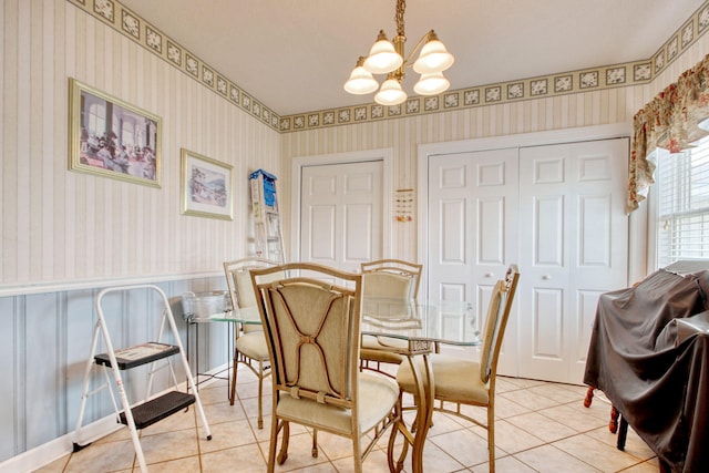 dining space with an inviting chandelier, light tile patterned flooring, and wallpapered walls
