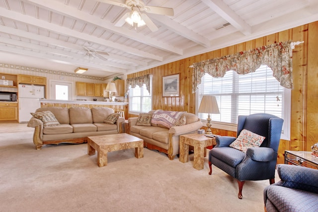 living room featuring beamed ceiling, ceiling fan, light colored carpet, and a healthy amount of sunlight
