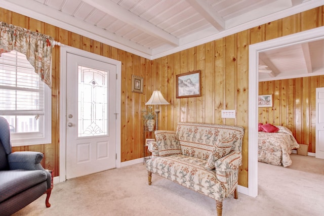 living area with wood walls, carpet, and beamed ceiling