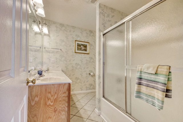 bathroom featuring tile patterned flooring, vanity, wallpapered walls, baseboards, and combined bath / shower with glass door