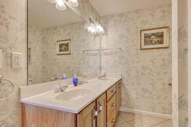 bathroom featuring a sink, baseboards, tile patterned flooring, and double vanity