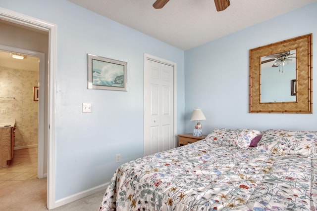 bedroom featuring baseboards, ceiling fan, a closet, and light colored carpet