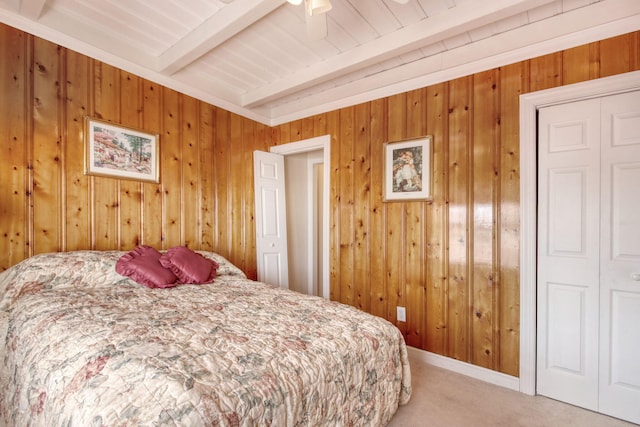 bedroom featuring wood walls, beam ceiling, and light carpet