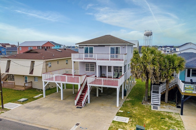 beach home with a front lawn, roof with shingles, a balcony, and stairway