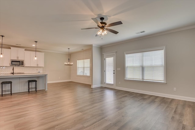 5265 Greyton Cir, North Augusta, SC 29860 - unfurnished living room featuring ceiling fan, light wood-style floors, ornamental molding, baseboards, and a chandelier