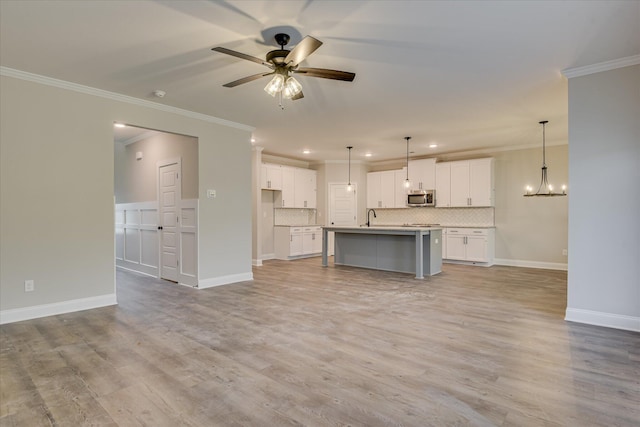 5265 Greyton Cir, North Augusta, SC 29860 - unfurnished living room with ornamental molding, a ceiling fan, a chandelier, light wood-style floors, and baseboards