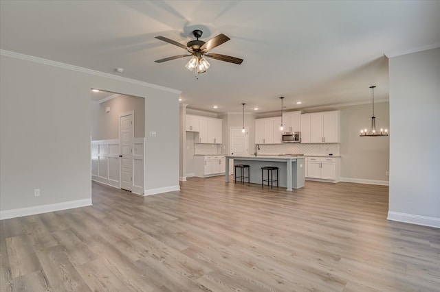 5265 Greyton Cir, North Augusta, SC 29860 - unfurnished living room featuring crown molding, a sink, a ceiling fan, a chandelier, and light wood-type flooring