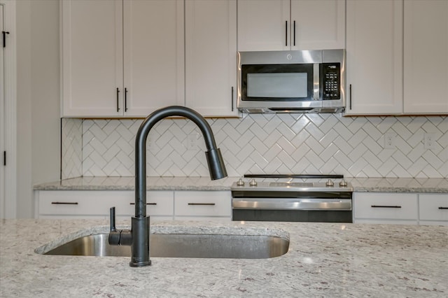 5265 Greyton Cir, North Augusta, SC 29860 - kitchen featuring stainless steel microwave, a sink, white cabinets, backsplash, and light stone countertops