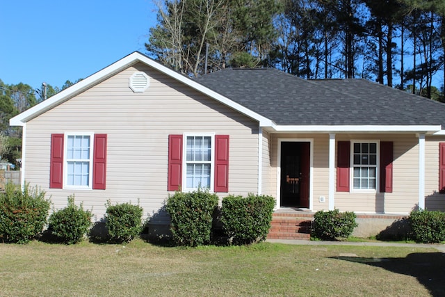 view of front of property featuring a shingled roof and a front lawn