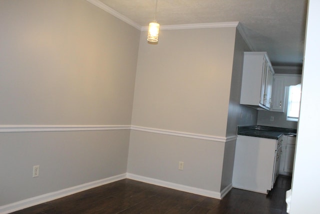 unfurnished dining area featuring dark wood-type flooring, crown molding, and baseboards