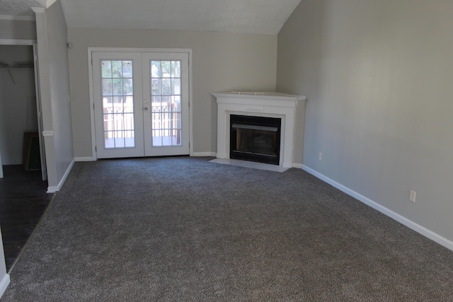 unfurnished living room featuring dark colored carpet, french doors, a fireplace with flush hearth, and baseboards