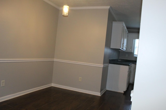 unfurnished dining area with dark wood-type flooring, baseboards, and ornamental molding