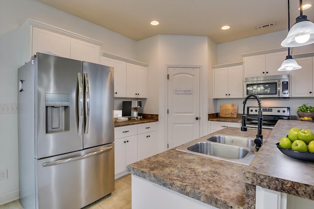 kitchen featuring hanging light fixtures, stainless steel appliances, sink, and white cabinets