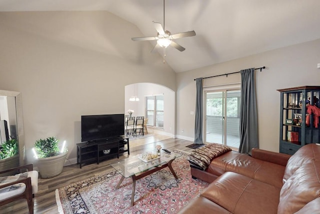 living room with arched walkways, ceiling fan, wood finished floors, baseboards, and high vaulted ceiling