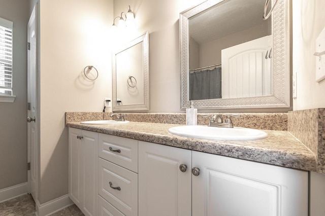 full bathroom with double vanity and baseboards