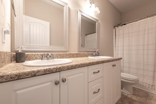 full bathroom featuring double vanity, toilet, and tile patterned floors
