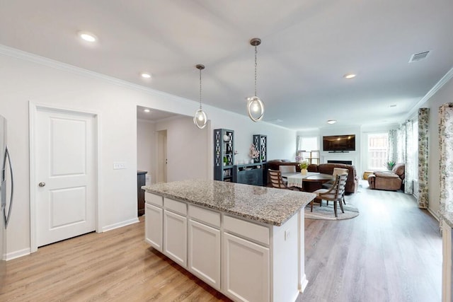 6134 High Top Ln, Aiken, SC 29801 - kitchen with a center island, light wood-style floors, ornamental molding, white cabinets, and hanging light fixtures