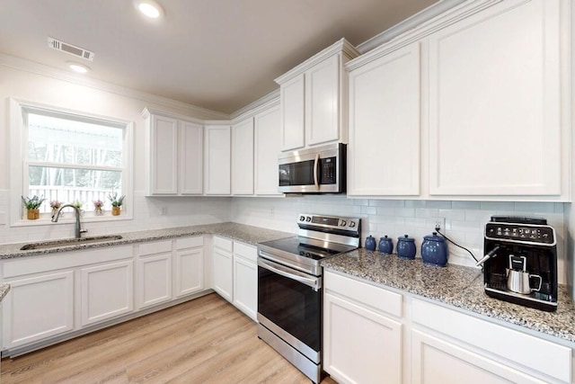 6134 High Top Ln, Aiken, SC 29801 - kitchen featuring appliances with stainless steel finishes, a sink, white cabinets, tasteful backsplash, and ornamental molding