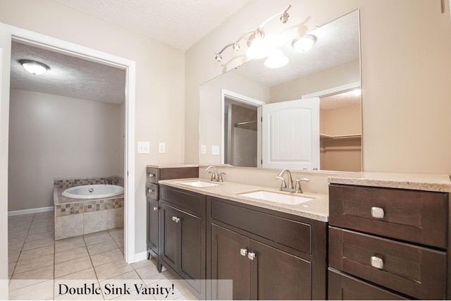 bathroom with vanity, tile patterned flooring, a textured ceiling, and tiled tub