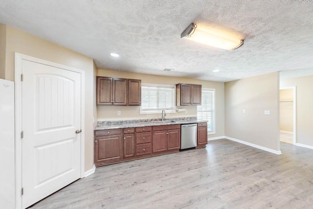 kitchen featuring dishwasher, sink, a textured ceiling, and light wood-type flooring