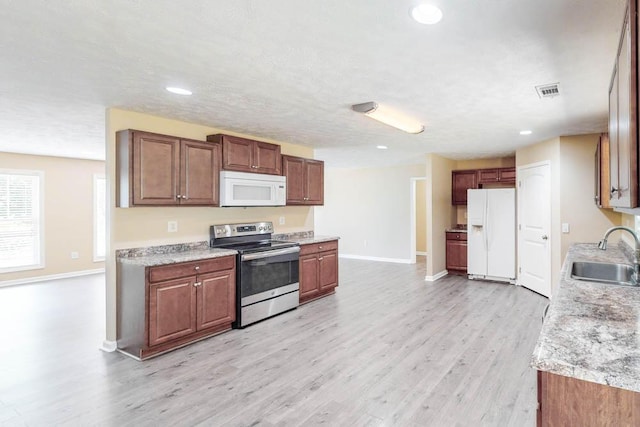 kitchen featuring white appliances, sink, a textured ceiling, light hardwood / wood-style floors, and light stone counters