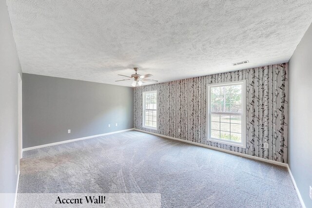 carpeted empty room with ceiling fan and a textured ceiling