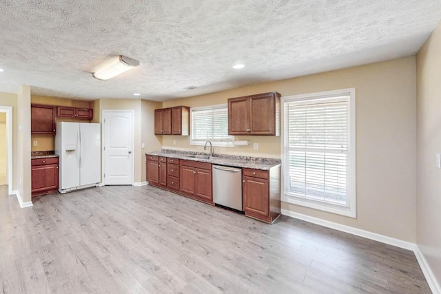 kitchen with white fridge with ice dispenser, sink, light hardwood / wood-style flooring, stainless steel dishwasher, and a textured ceiling