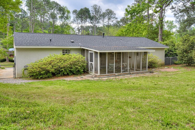 back of house featuring a sunroom, a shingled roof, a lawn, and fence