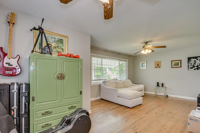interior space with baseboards, a ceiling fan, and light wood-style flooring
