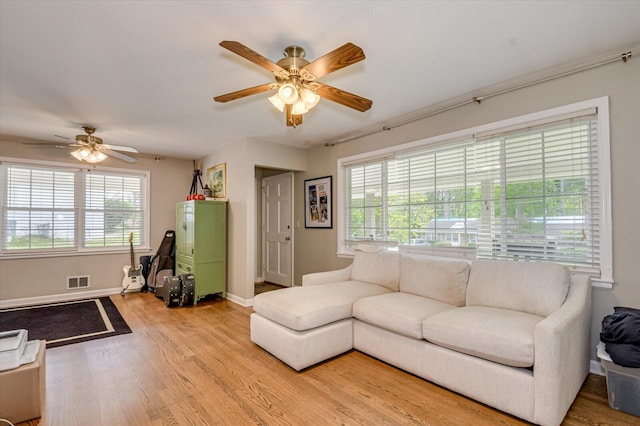 living room with visible vents, a ceiling fan, light wood-style floors, and a wealth of natural light