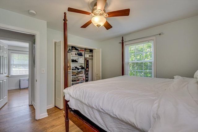 bedroom featuring light wood-style floors, multiple windows, a ceiling fan, and a closet